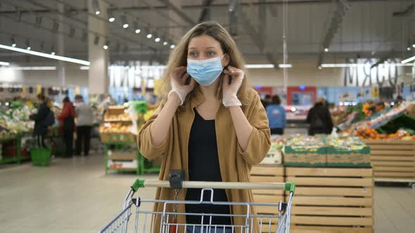 Girl Puts on a Medical Mask in a Supermarket To Protect Herself From the Coronavirus Pandemic