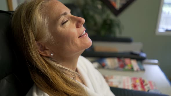 Mature woman is happy while she gets her toenails filed by pedicurist. Steadicam shot.