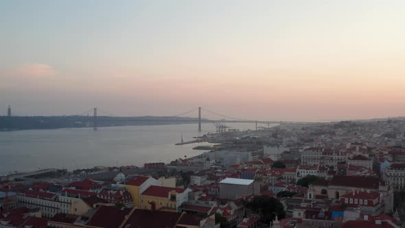 Slider Aerial View of Ponte 25 De Abril Red Bridge in Lisbon Portugal with Rooftops of Houses in the