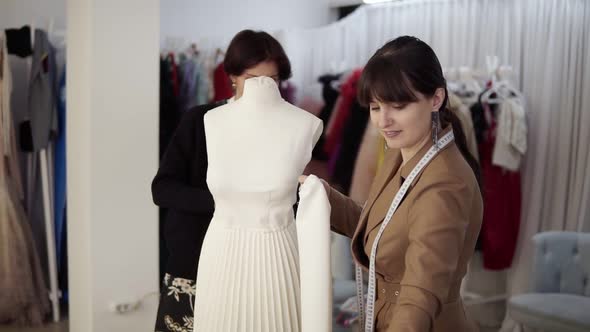 Two Professional Tailors Designers Working with New Model Tailoring Dress on Mannequin in Studio