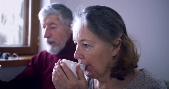 an Elderly Couple Drinks Tea or Coffee in Their Cozy House Talking About Something