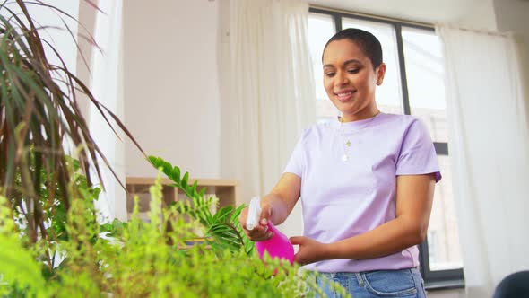 Woman Spraying Houseplant with Water at Home