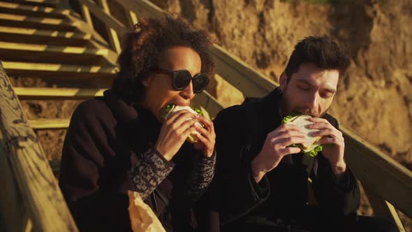 Man and Woman Biting Sandwich Outside Happy Slow Motion