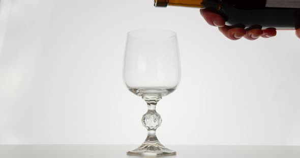 Close-up Shot. The Red Wine Is Pouring Into a Glass, White Background