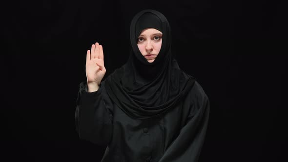 Middle Shot of Depressed Terrified Muslim Woman Raising Palm with Tuck Thumb Looking at Camera