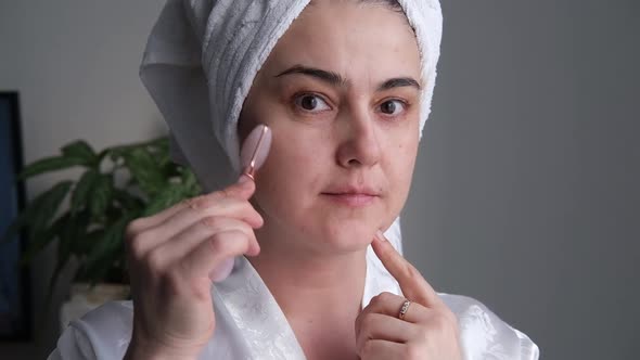 A Closeup Photo of a Young Woman Looking Relaxed and Smiling Doing a Massage with a Face Roller Made