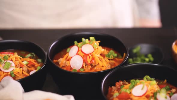 Close up of turkey chili garnished with fresh radishes, green onions and cheddar cheese.