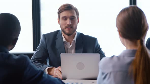 Caucasian young man in a suit talking with colleagues at a business meeting