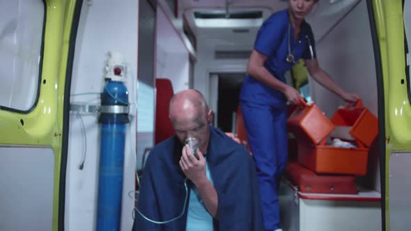 Sick Man Sit in Oxygen Mask in Ambulance Car.