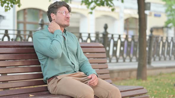 Man having Neck Pain while Sitting on Bench