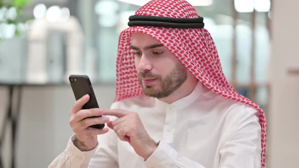 Arab Businessman Celebrating Success on Smartphone in Office