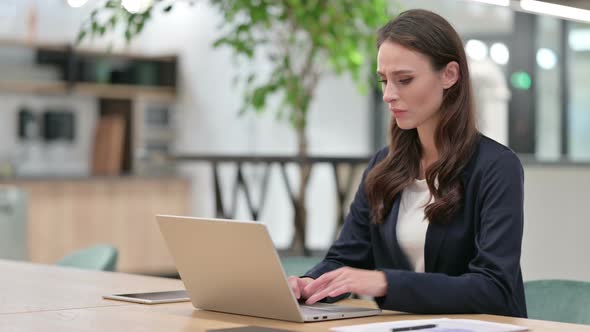 Businesswoman with Back Pain Using Laptop at Work 