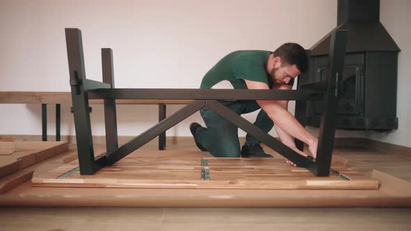 Man Assembling DIY Table, Fastening Metal Legs To Tabletop. static