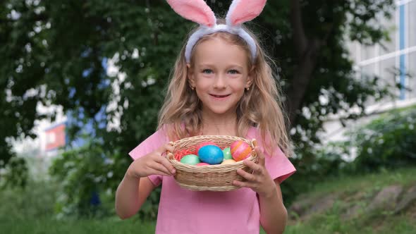 Little Girl Holds Basket of Easter Eggs Outdoors