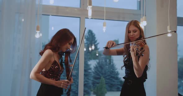 Duet of Happy Female Violinists in Black Dresses Performing Instrumental Music