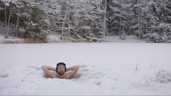 ZOOM IN - A handsome, rugged hipster man relaxes in his ice hole