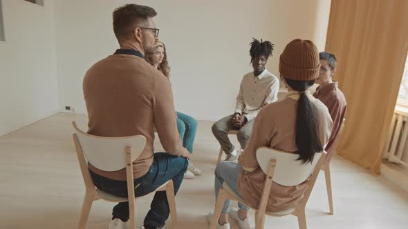 Female Specialist Talking to Group of People at Therapy Session