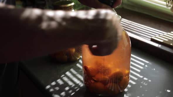 A Man Rolls Up a Jar of Fruit Preserves