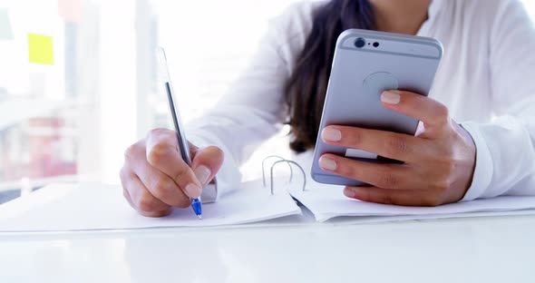 woman using smartphone and taking notes