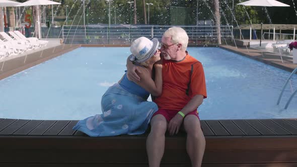 Happy Mature Couple Sitting on the Edge of the Pool