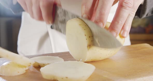 Slow motion of a chef slicing a potato using a sharp large knife