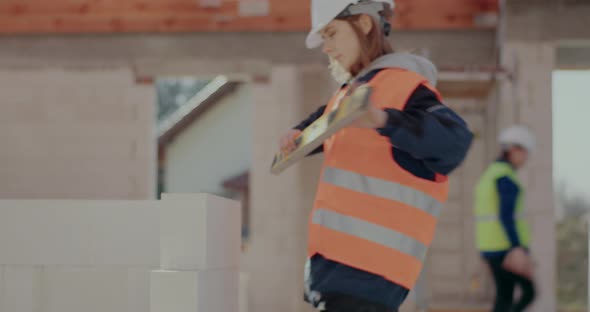 Female Construction Worker Examining Concrete Wall with Level