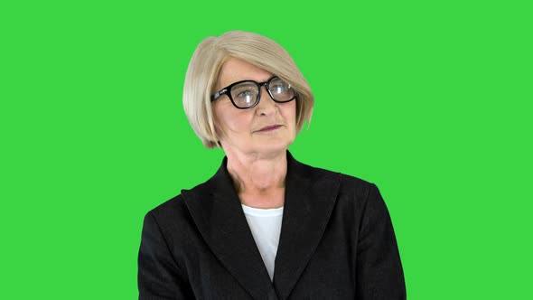 Charming Elder Woman in Fashionable Glasses Standing and Waiting on a Green Screen Chroma Key