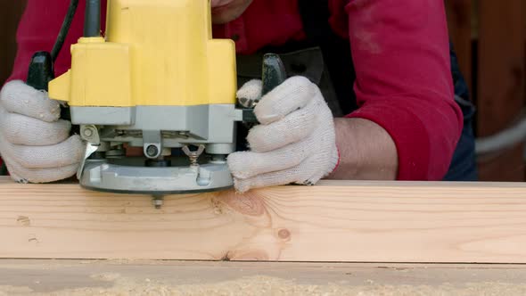 Csucasian Carpenter Processes Wood Beam with Milling Machine.