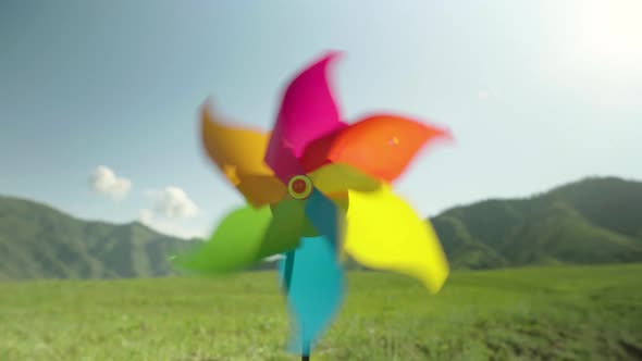 Colored Pinwheel Spins Quickly in the Wind Closeup Against the Backdrop of Mountains and the Sky