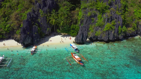 Tourists Enjoy Azure Sea and Tropical Island on the Entalula Beach in El Nido, Palawan, Philippines.