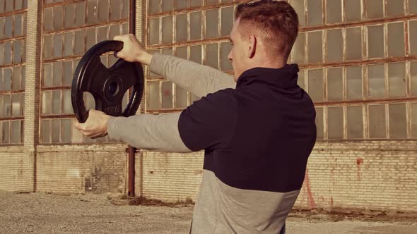 Young and fit man having evening workout outdoor. Urban sunset background.