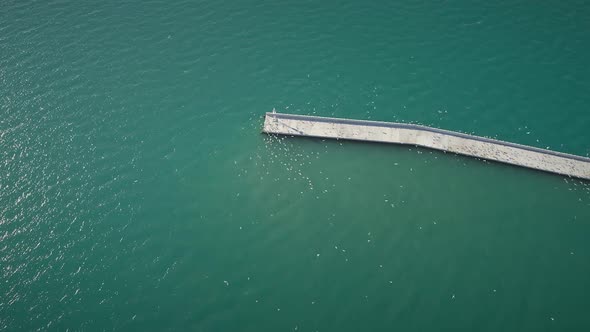 Aerial view of seagulls flying around concrete pier located on the sea in Greece