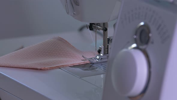 Hands sewing a peach fabric