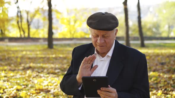 Happy Man Waving His Hand to the Tablet Camera When Communicating in Park