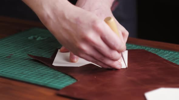 Man Tailor Cutting Artificial Leather with Ruler Closeup