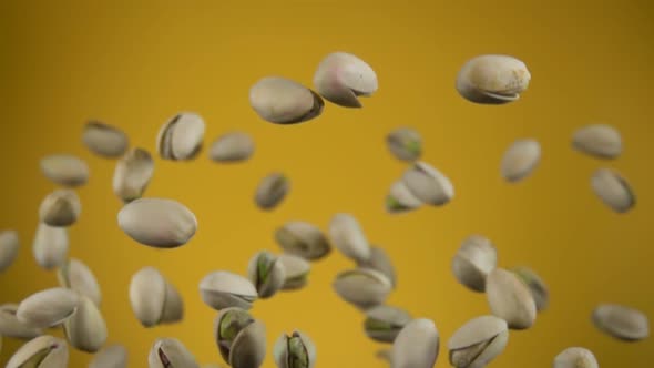 Closeup of Salted Pistachios Flying Up on a Yellow Background