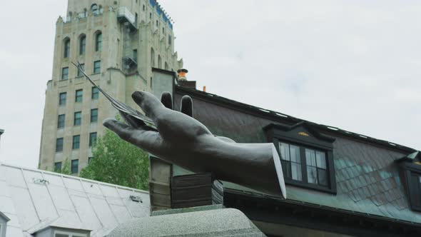 A hand holding a quill sculpture