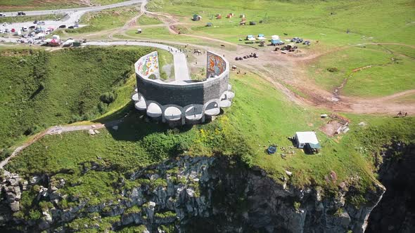 Aerial drone view of a memorial on the edge of a cliff in Caucasus Mountains, Georgia. Greenery, val