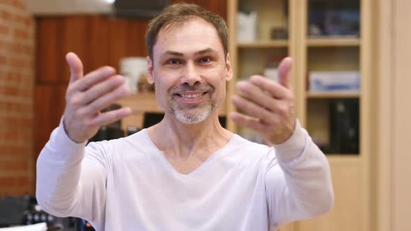 Inviting Gesture By Middle Age Man in Office