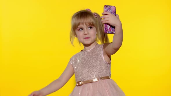 Child girl using smartphone Portrait of blonde kid emotionally makes selfie on mobile phone