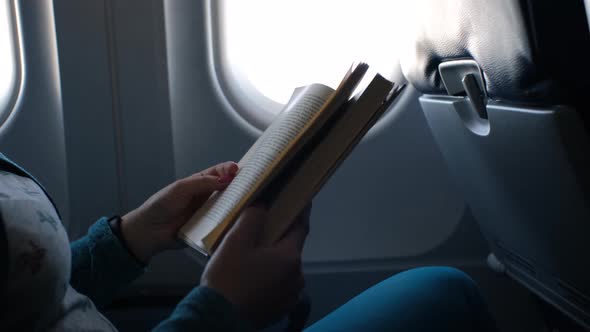 Closeup of Woman Reading Book at Seat in Airplane
