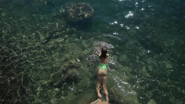 Slowmotion Top View Sexy Slim Woman with Nise Buttocks in Green Swimsuit Floating in Clear Turquoise