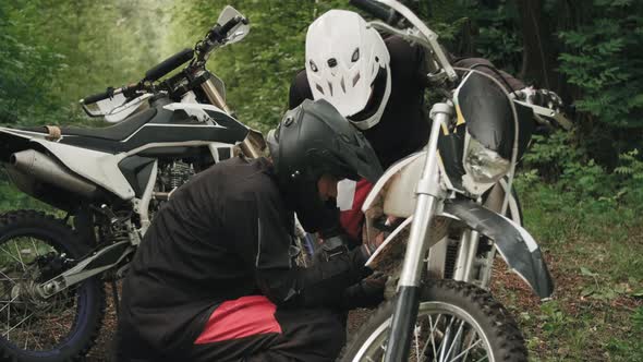 Riders in Helmets Fixing Motorcycle in Forest