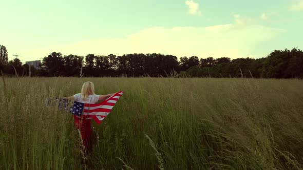 American Woman Covered with Flag of America at Sunset on Wheat Field