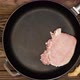 The cook puts raw meat steaks in a frying pan. Sliced pork meat in a cast iron skillet. Fry - VideoHive Item for Sale