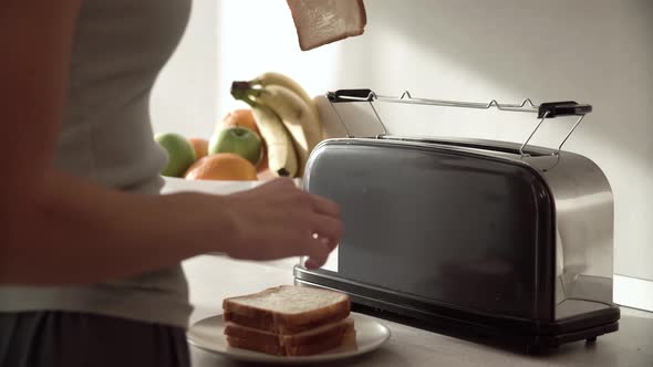 Breakfast. Woman Putting Slicing Bread In Toaster Closeup
