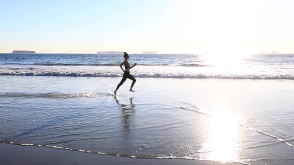 Slow motion shot of an Asian woman jogging on the beach