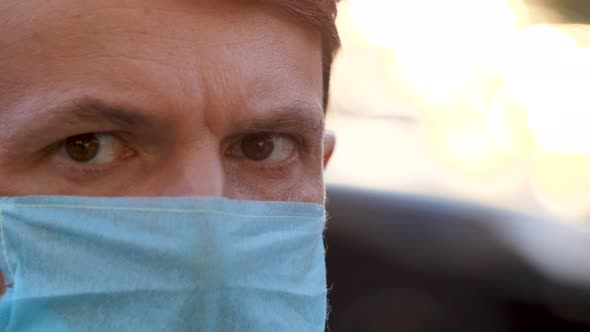 Man in a Disposable Mask Looking To Camera Standing at Street. Portrait of Young Guy in Medical Mask