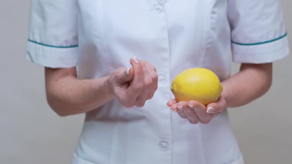 Nutritionist Doctor Healthy Lifestyle Concept - Holding Lemon Fruit and Medicine or Vitamin Pills