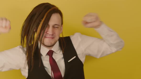 Young Man with Long Dreadlocks Dancing on Yellow Background